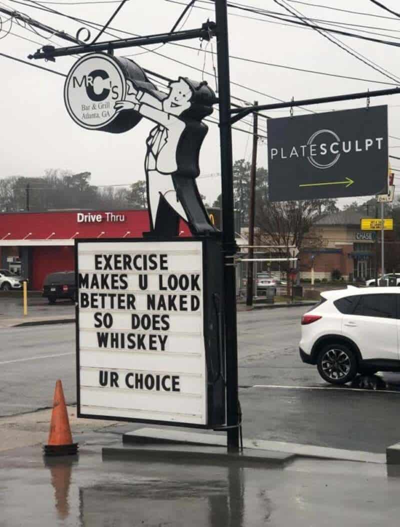 Sign with humorous message about exercise, whiskey, and choices.