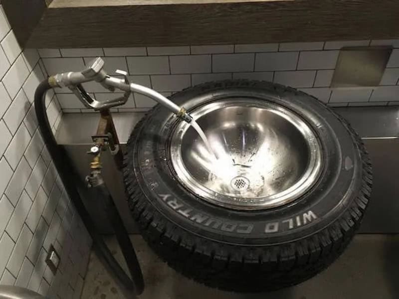 Sink with a tire as the basin and a faucet pouring water into it.
