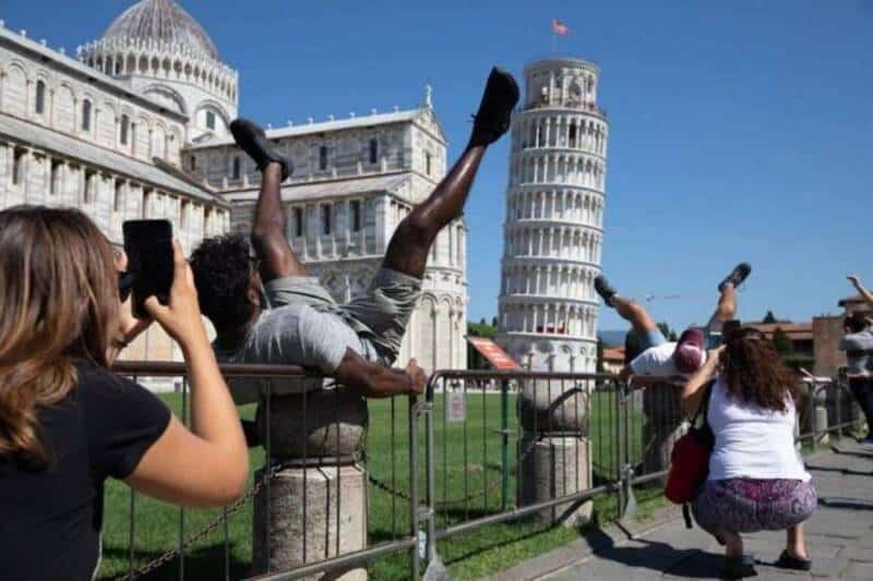People taking photos and posing with the Leaning Tower of Pisa in Italy.
