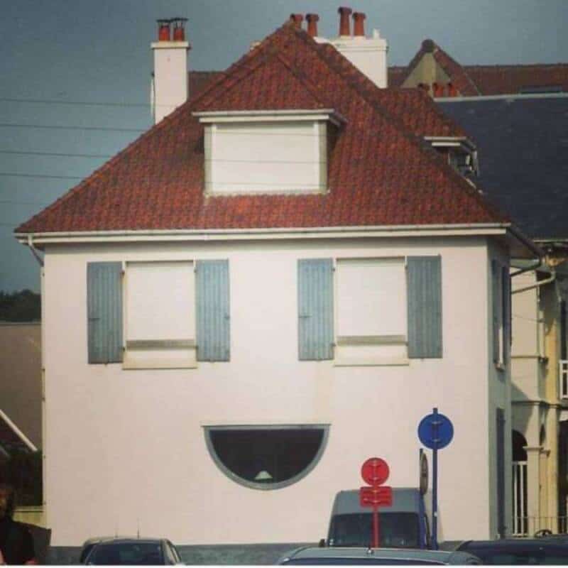 Building with a face-like appearance, smiling window and blue shutters.