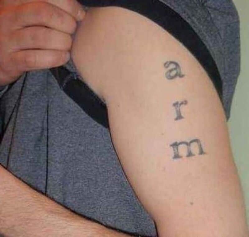 Tattoo on arm spelling 'arm' with a person pulling up sleeve.