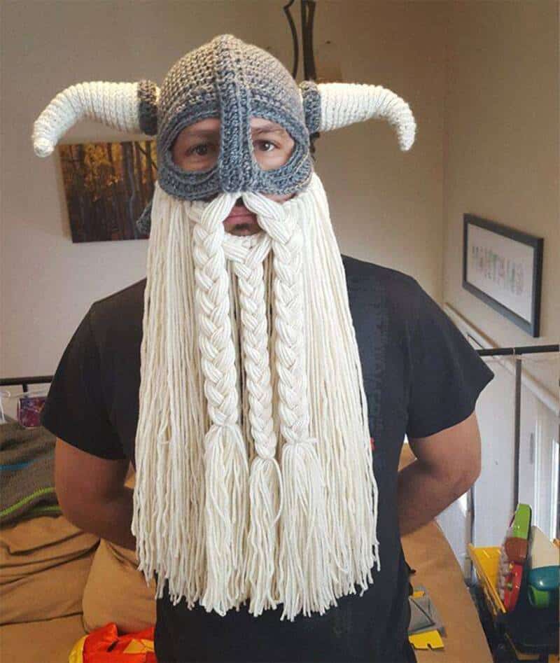 Person wearing a Viking helmet with horns and a long white braided beard.