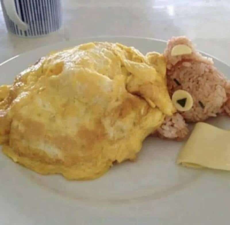 Omelette with rice shaped like a bear's face on a plate.