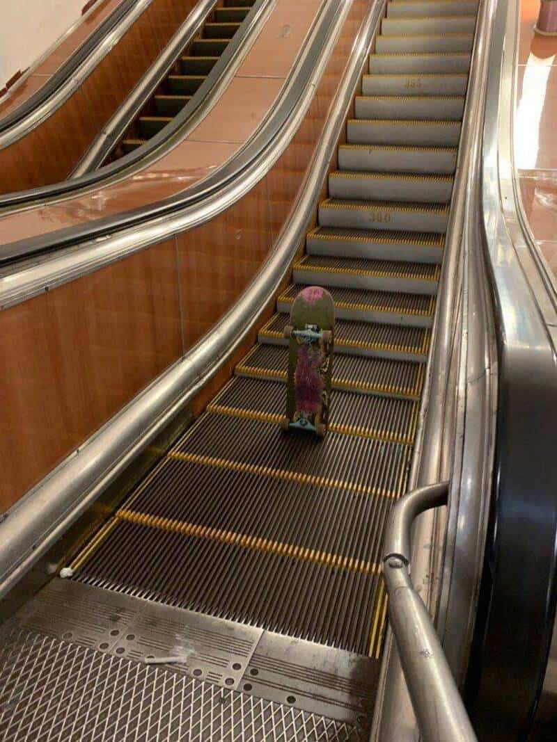 A skateboard on an escalator in a shopping mall.