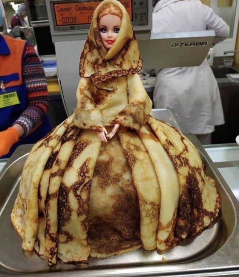 Doll dressed in a dress made of crepes, resembling a princess in a bakery setting.