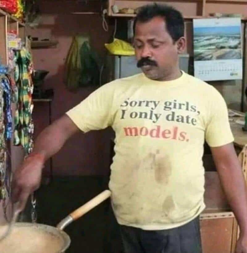 Man in yellow T-shirt with text, cooking in a kitchen.