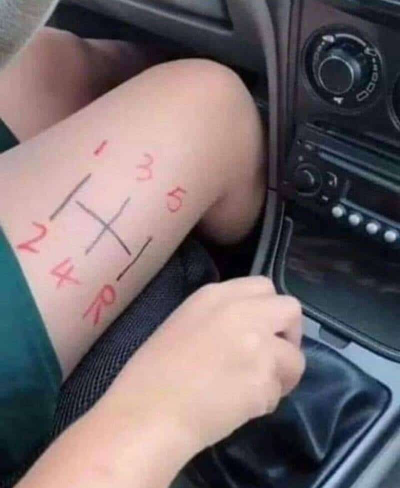 Tic-tac-toe game drawn on a person's thigh with numbers 1-5 and a cross.