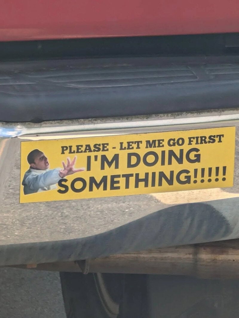Sign says 'Please - Let me go first. I'm doing something!!!!!' with a man pointing.