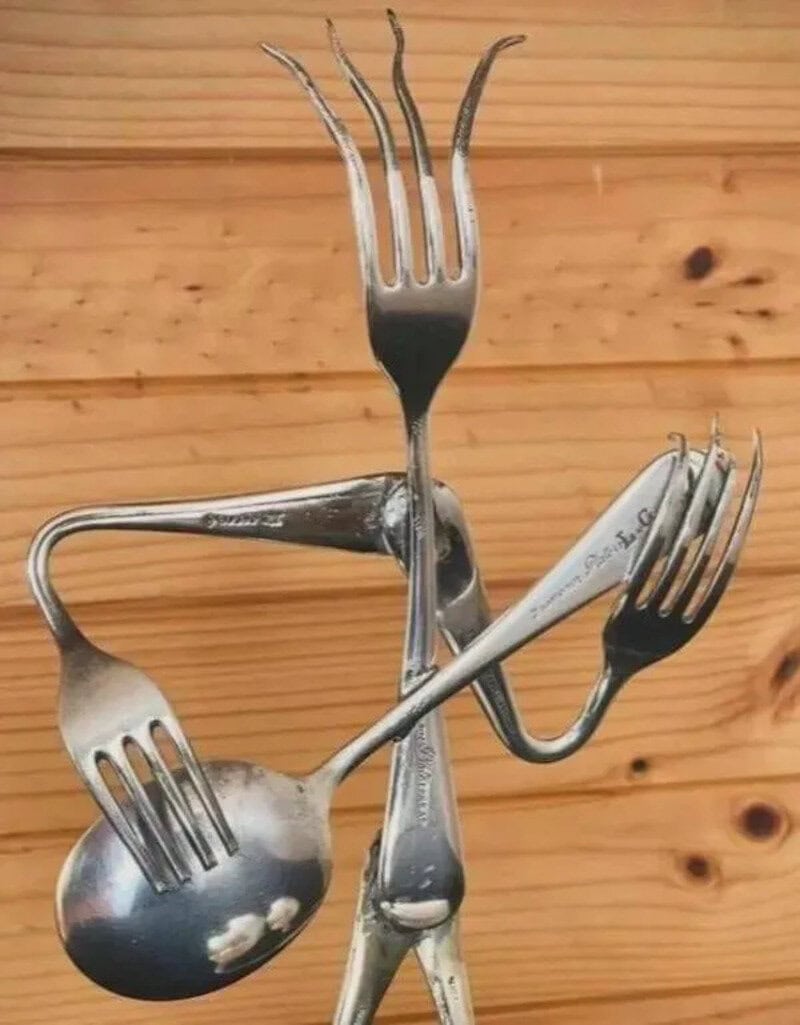 Artistic arrangement of four silver forks and a spoon on a wooden surface.