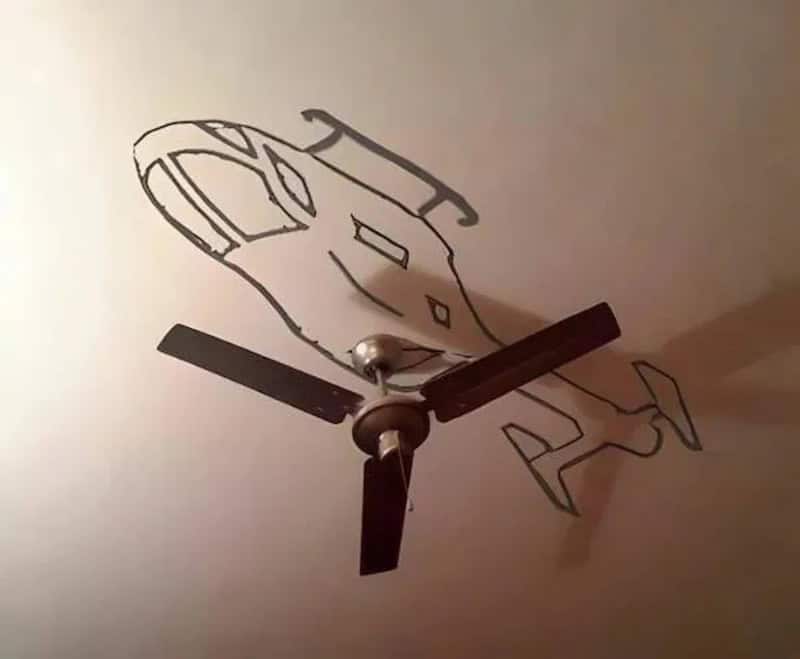 Ceiling fan with a shadow of a cartoonish face on the ceiling.
