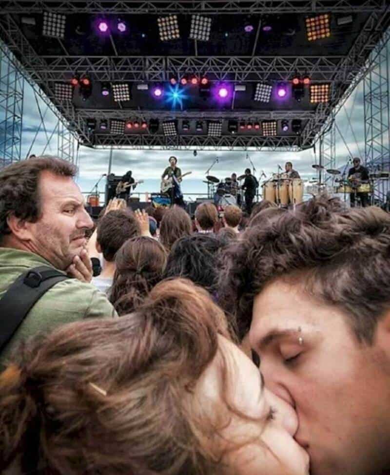 Live outdoor concert with band performing on stage and audience in front.