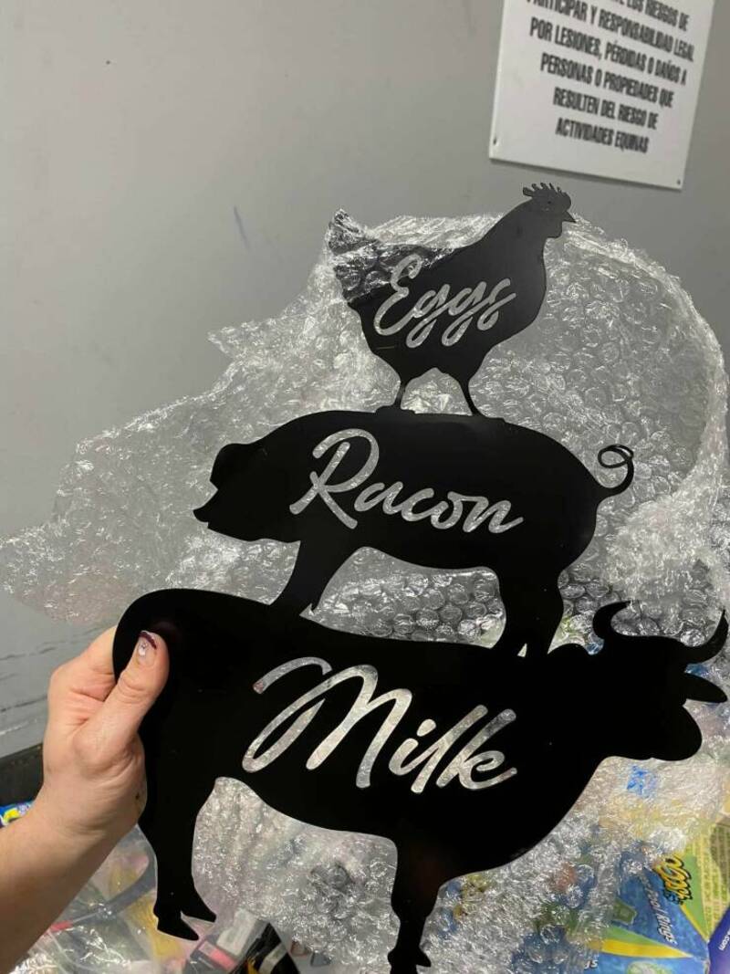 Black silhouette cutouts of a chicken, pig, and cow with labels "Eggs," "Racun," and "Milk".