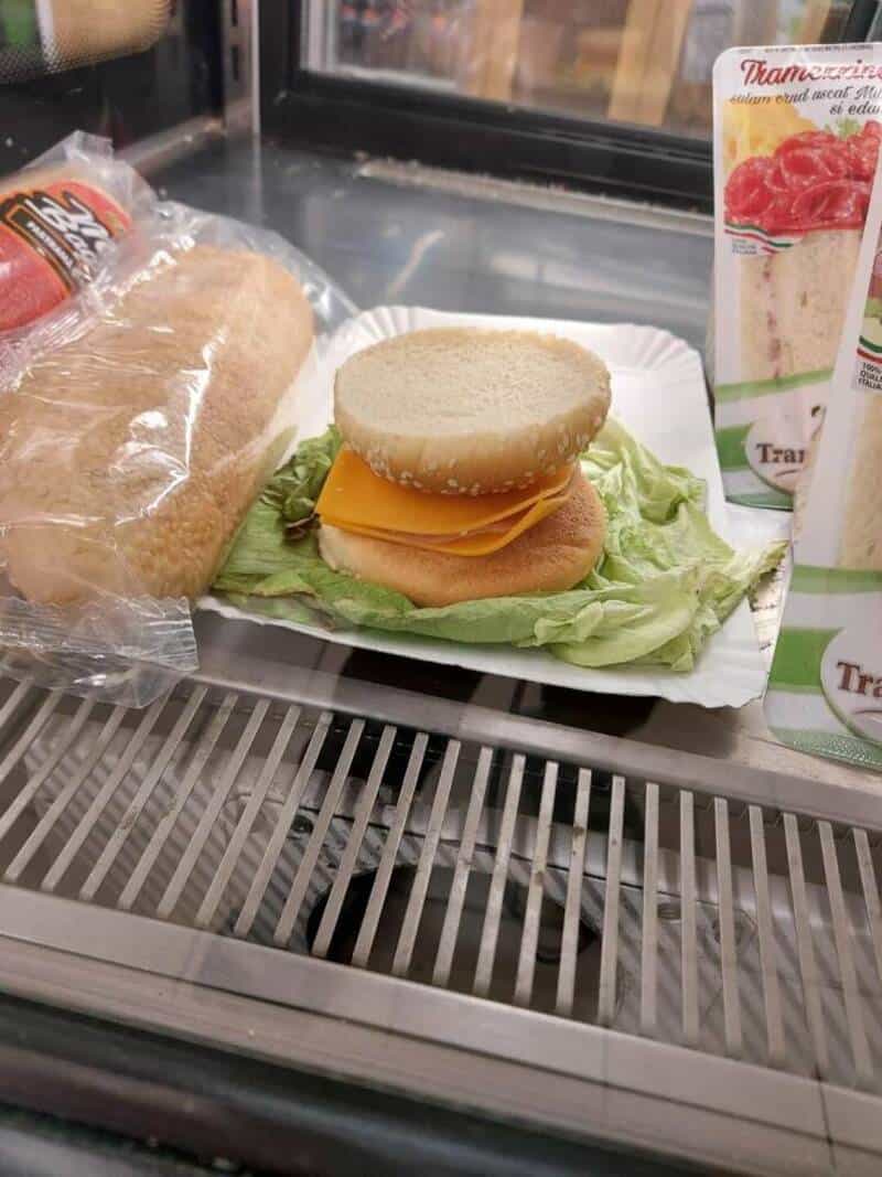 Sandwich with chicken patty, cheese, lettuce, and bun on a tray.