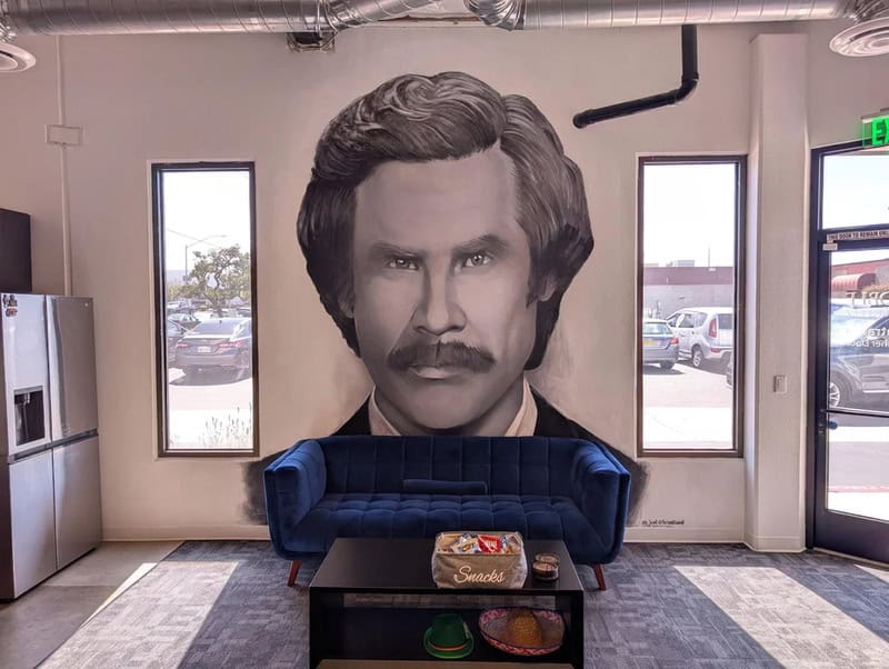 Large black and white portrait of a man with a mustache on a wall behind a blue sofa.
