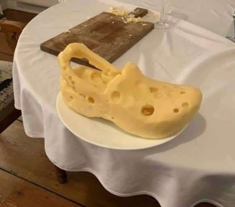 Large piece of Swiss cheese with holes on a white plate on a table.