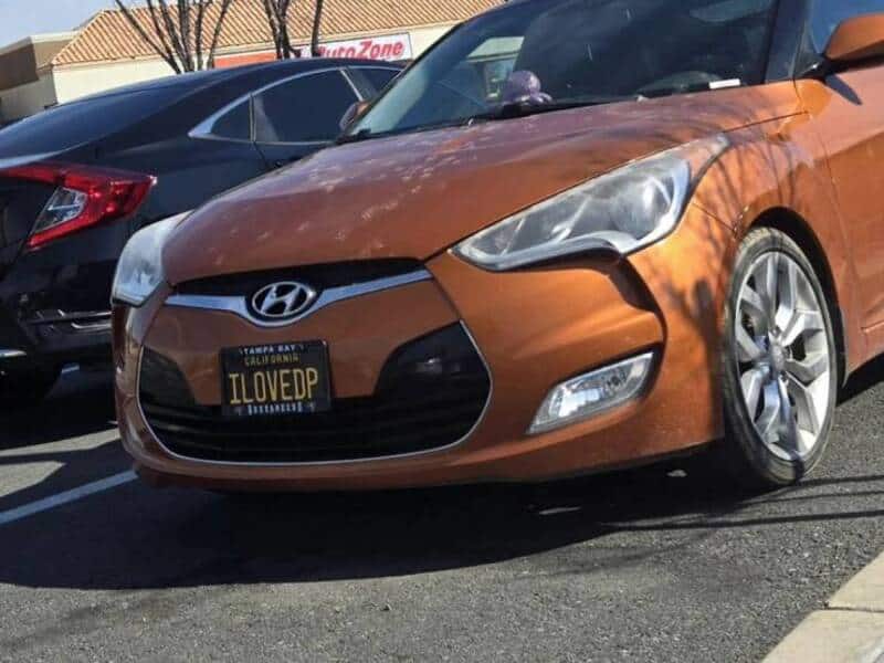 Orange Hyundai car with a custom "ILOVEDP" license plate in a parking lot.