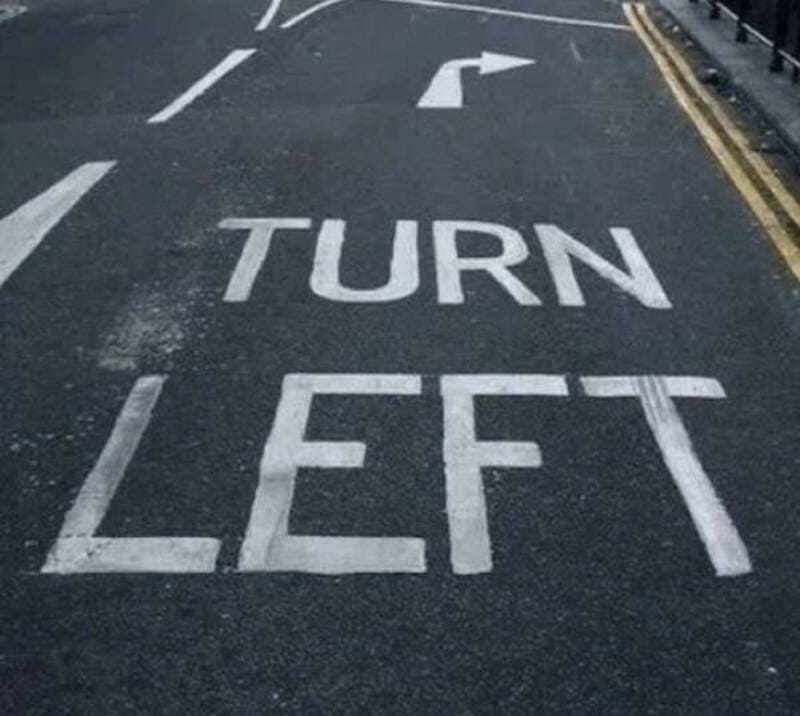 TURN LEFT road sign painted on asphalt with directional arrow.