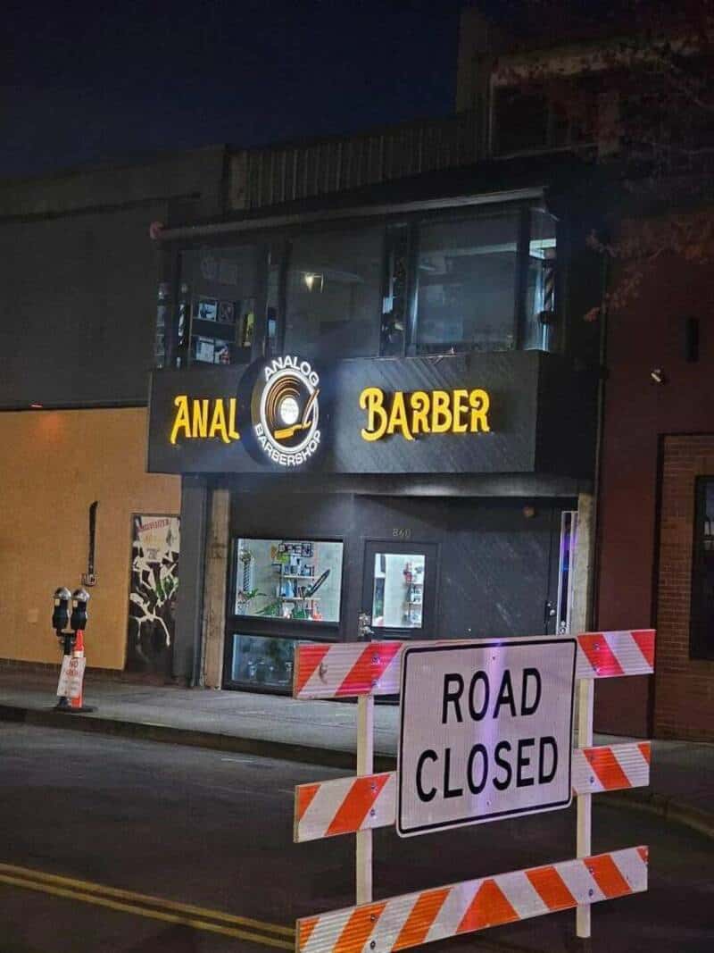 Closed barber shop with "Road Closed" sign at night.