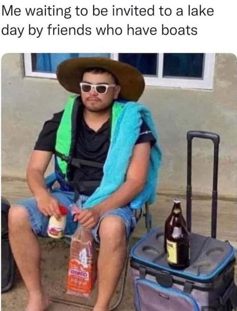 Relaxed man with sunglasses, hat, and backpack sitting outdoors with a suitcase, holding a drink, re.