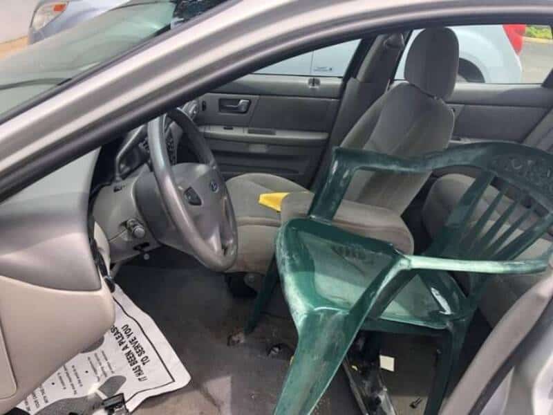 Broken green plastic chair inside a car, placed on the passenger seat.