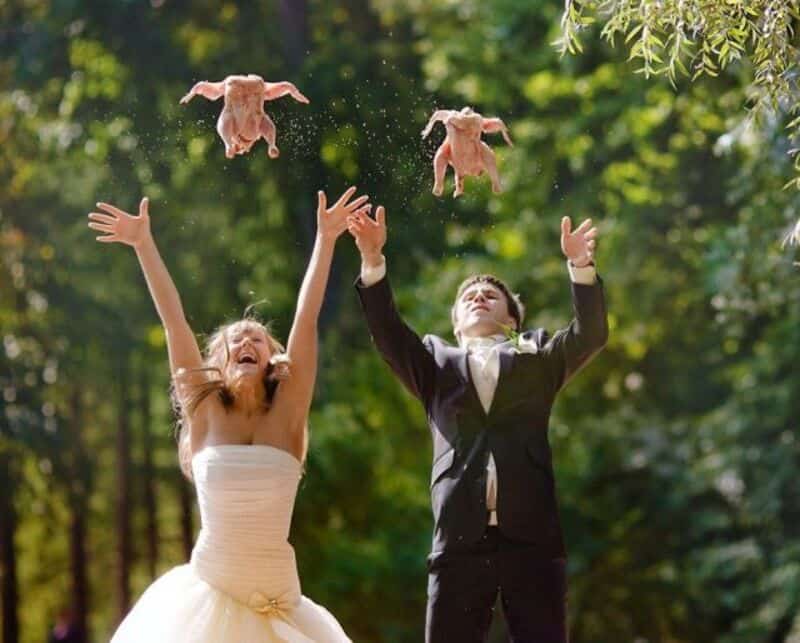 Bride and groom tossing stuffed animals into the air outdoors.