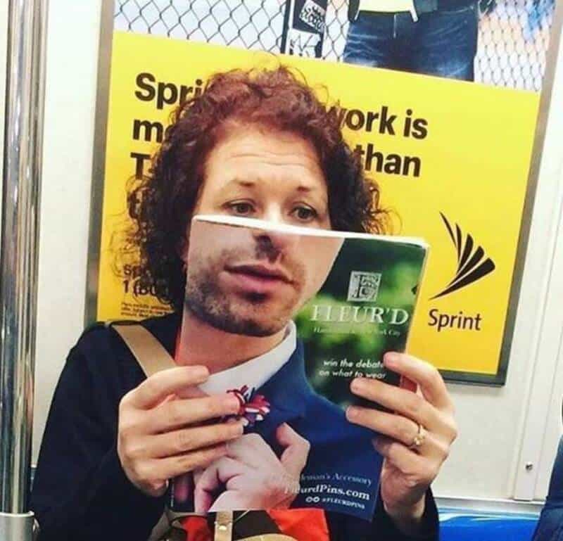 Woman holding a flyer with a man's face, on a train with a yellow ad in the background.