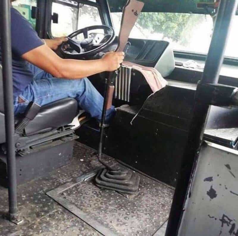 A bus driver holding a gear shift lever inside the vehicle.
