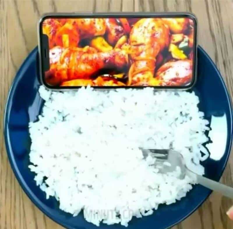 Phone placed on rice with a food image on the screen.