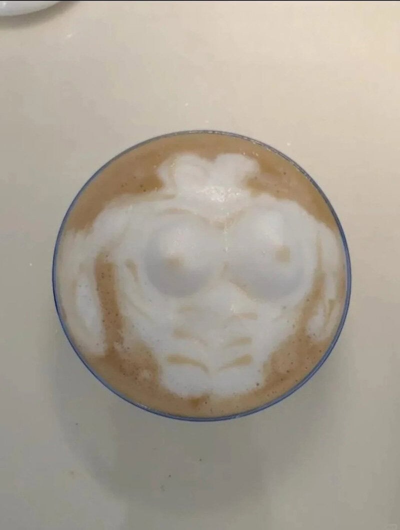 Latte art in the shape of a smiling face with glasses in a glass cup.