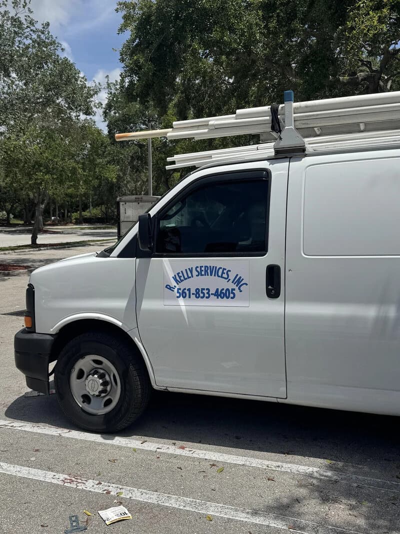 Service van with ladder rack and company info, parked outdoors.
