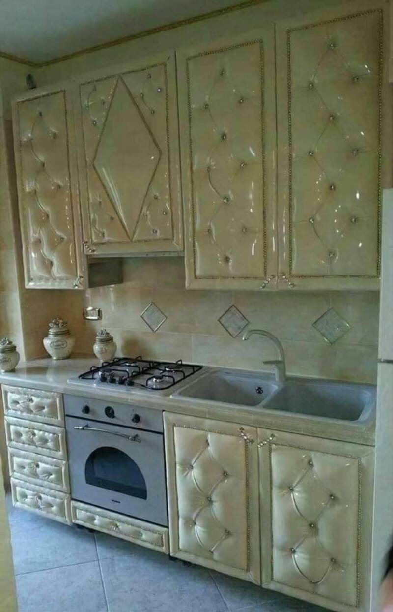 Luxurious cream-colored kitchen cabinets with tufted upholstery and crystal accents.