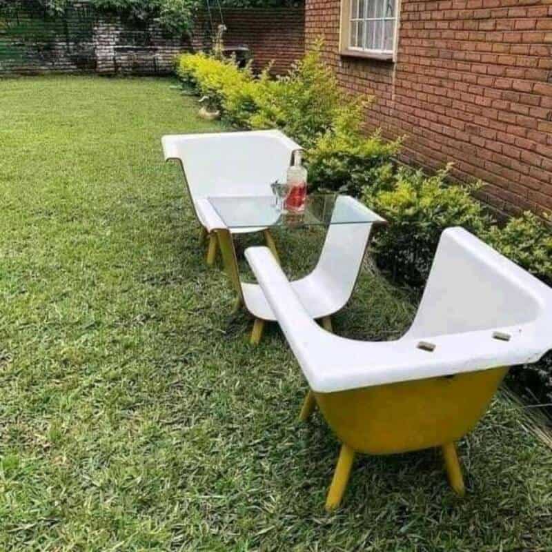 Bathtub repurposed as outdoor garden seating with a glass table and plants.