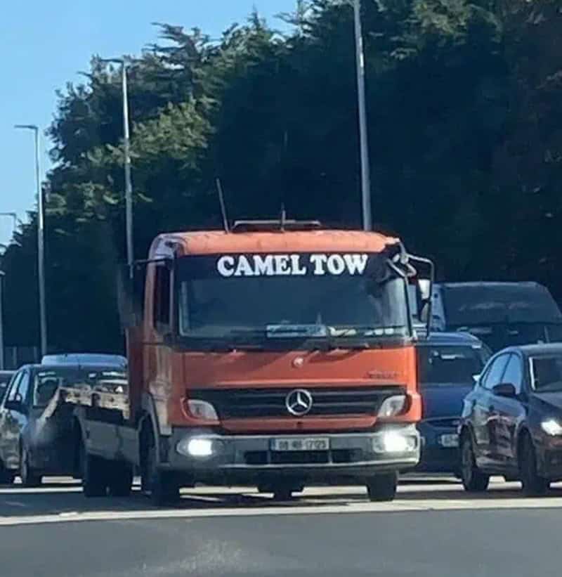 Camel Tow Mercedes-Benz truck with "CAMEL TOW" sign on the windshield, parked among other vehicles o.