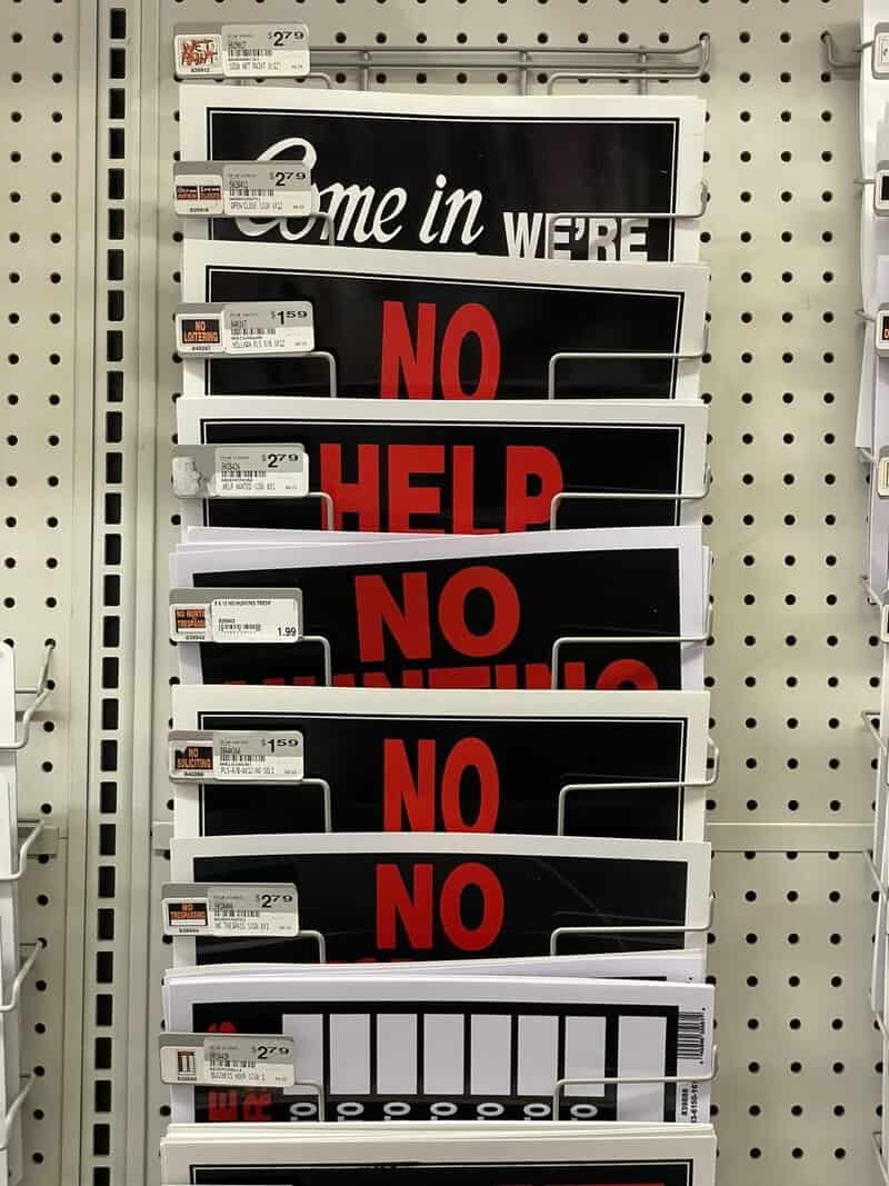 "Come in we're NO HELP NO HELP NO HELP" sign on a store shelf.
