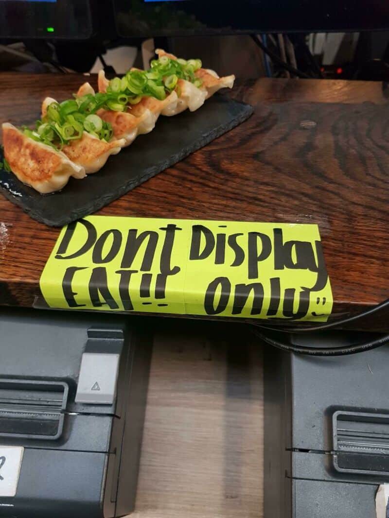 Don't display eat!! onigiri with green onions on a black slate plate on a wooden table.
