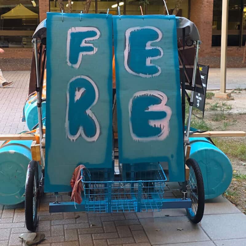 Free sign with blue and white letters on a cart outside.