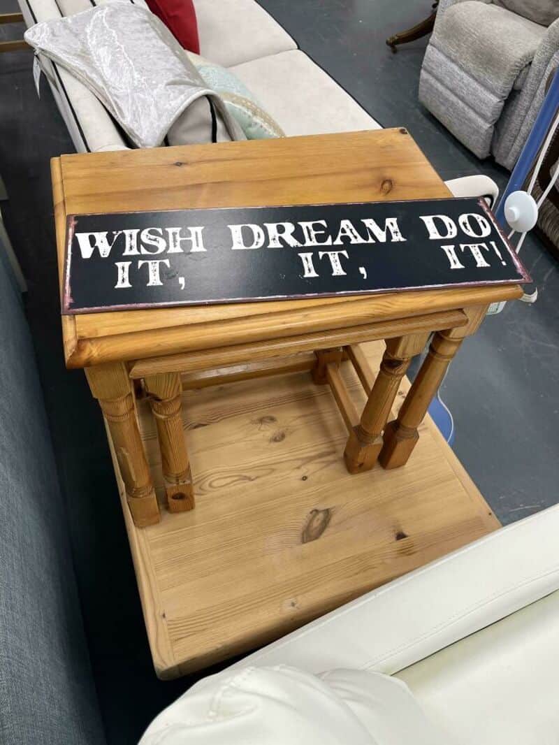 Wooden side table with a black and white sign reading "WISH IT, DREAM IT, DO IT!" on top.