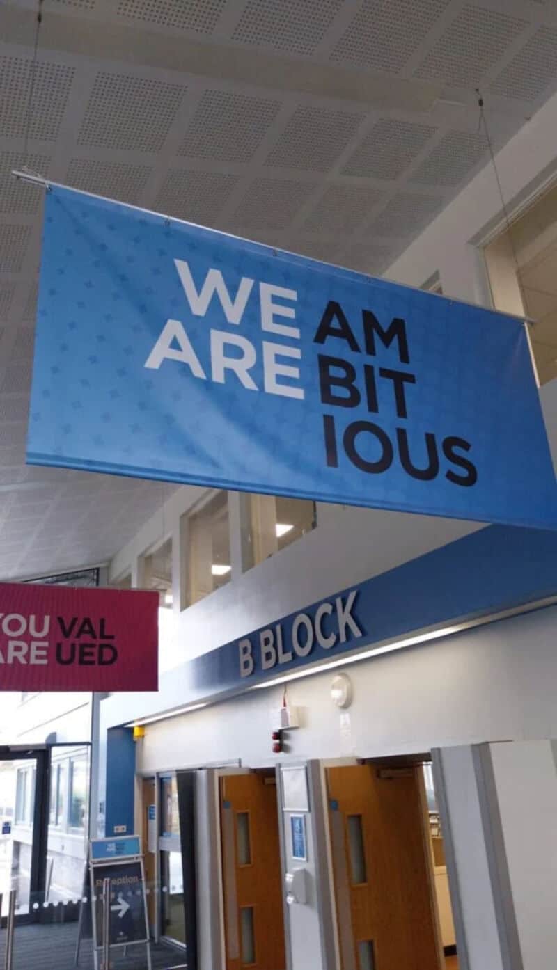 Blue banner with the text 'WE ARE BITIOUS' hanging in a building.