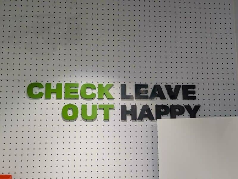 Check leave out happy sign on a perforated wall.