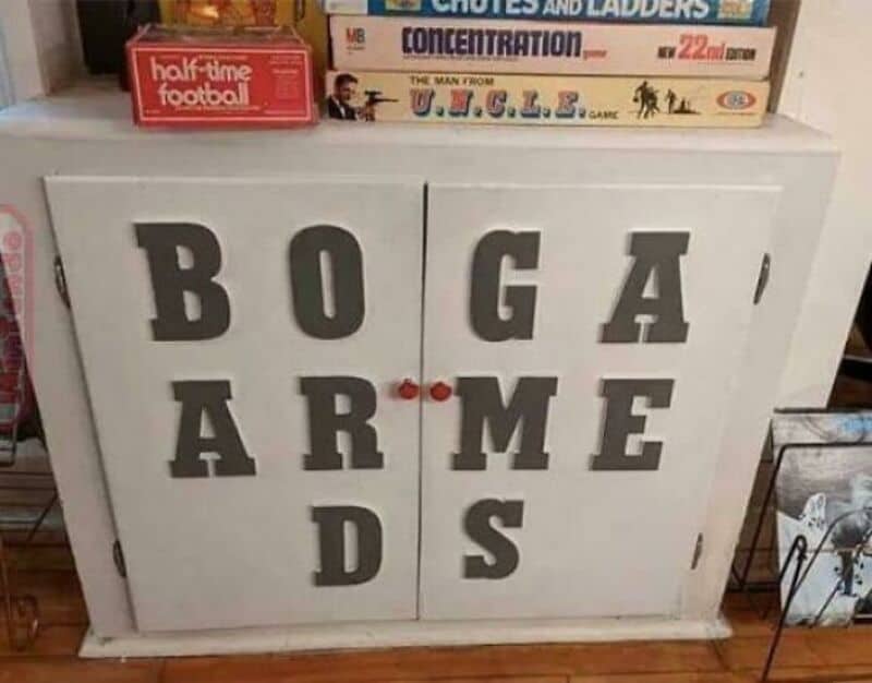 Cabinet with letters spelling 'BOGA' and 'ARME' on doors, with books on top.