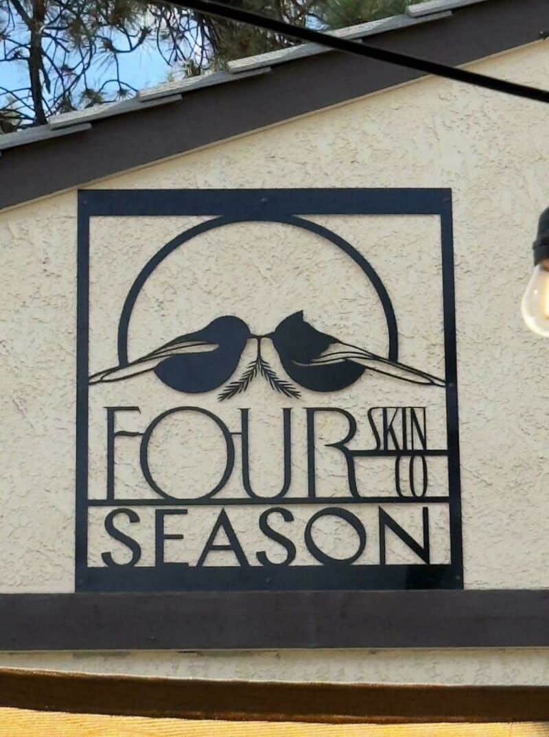 Sign reads 'FOUR SEASON SKIN' with two birds perched on a branch.
