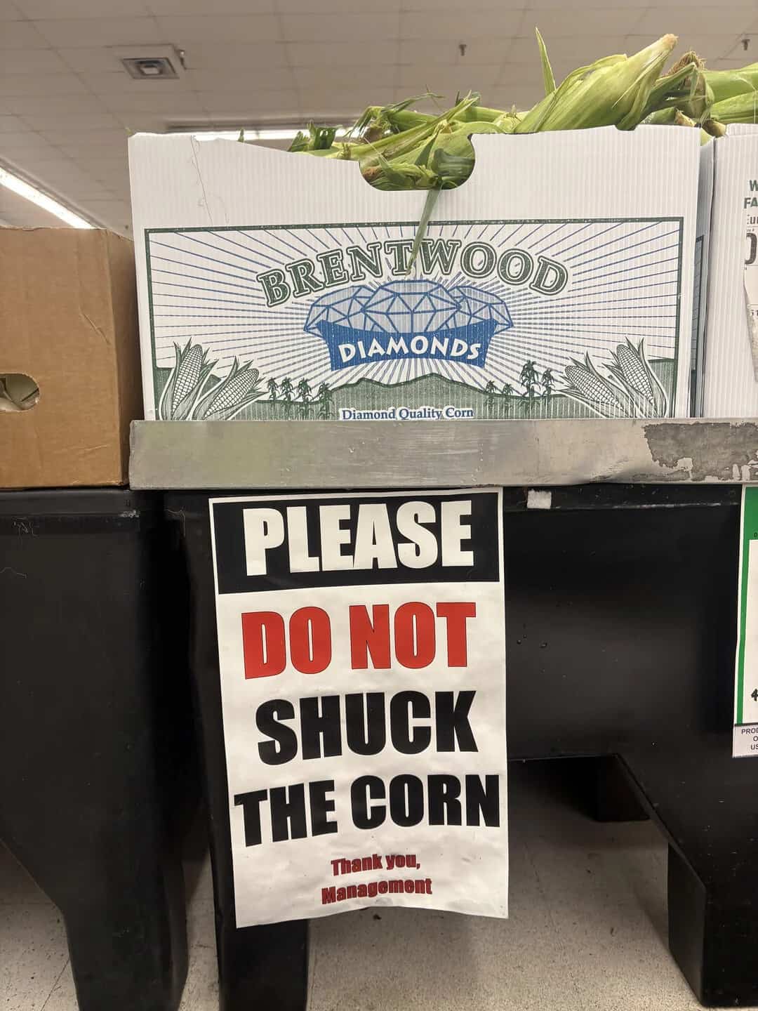 Sign reading 'Please do not shuck the corn' at a grocery store.