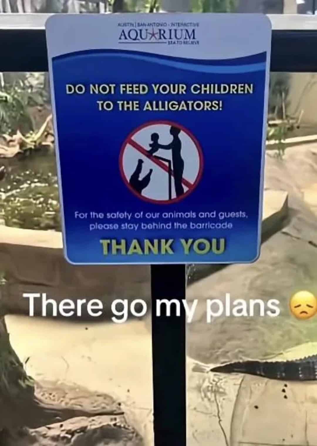 Do not feed children to alligators sign at aquarium with a sad face emoji.