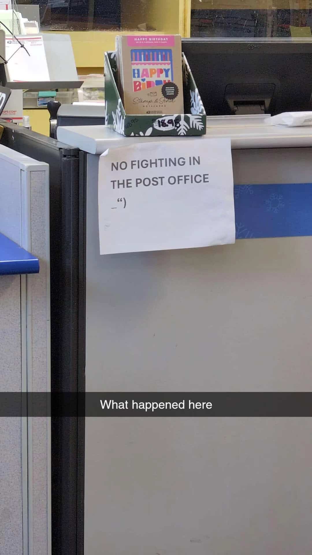 Sign on post office counter says 'NO FIGHTING IN THE POST OFFICE' with a smiley face.