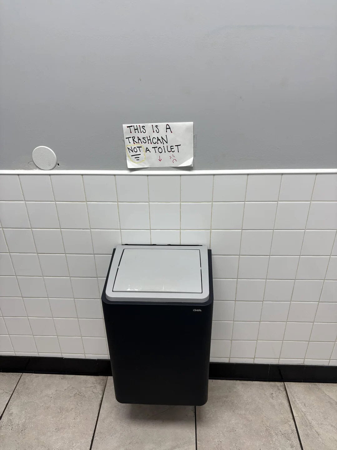 Sign says 'This is a Transcan not a toilet' above trash can.