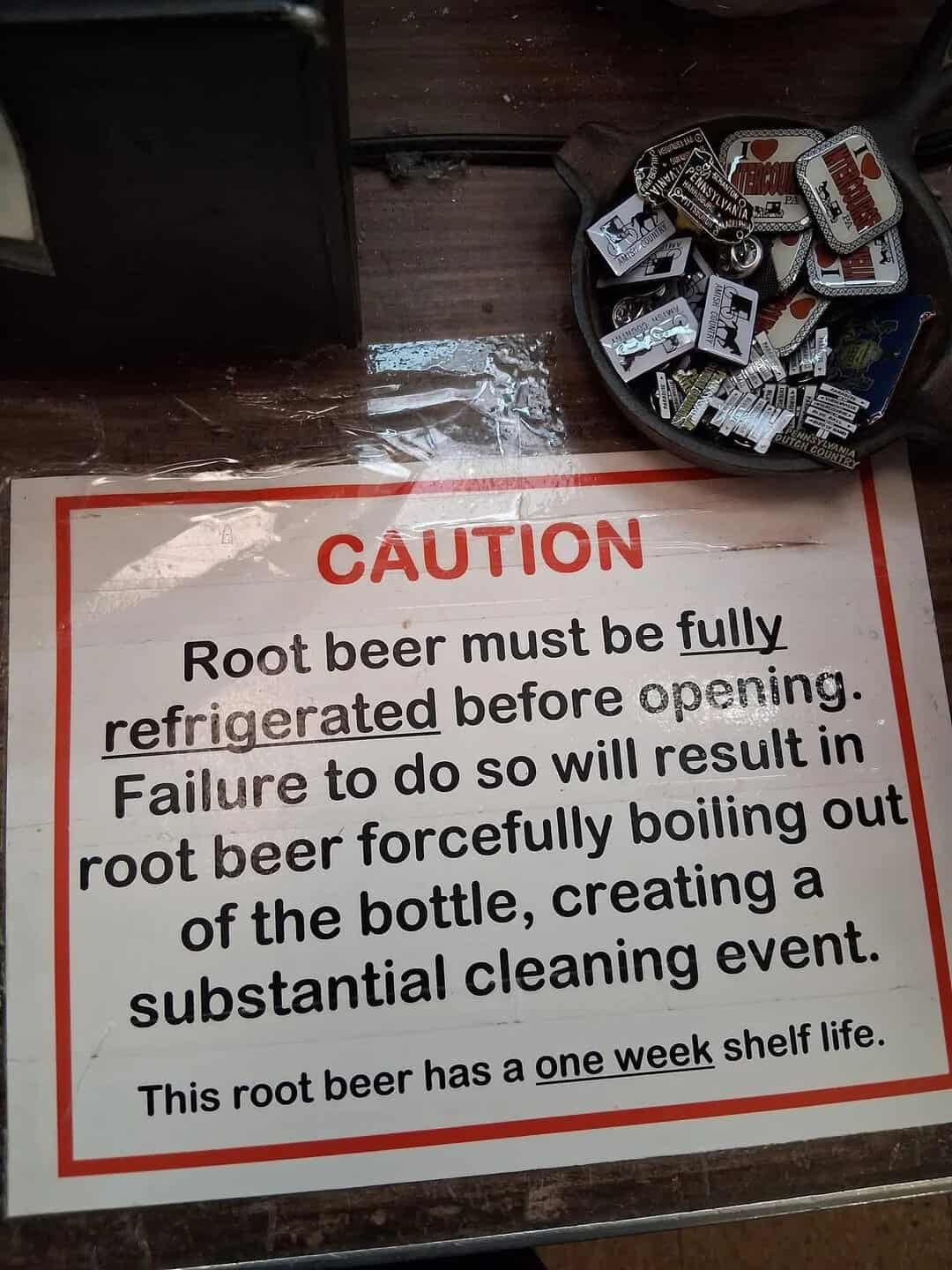 Caution sign about root beer with humorous instructions and one-week shelf life.