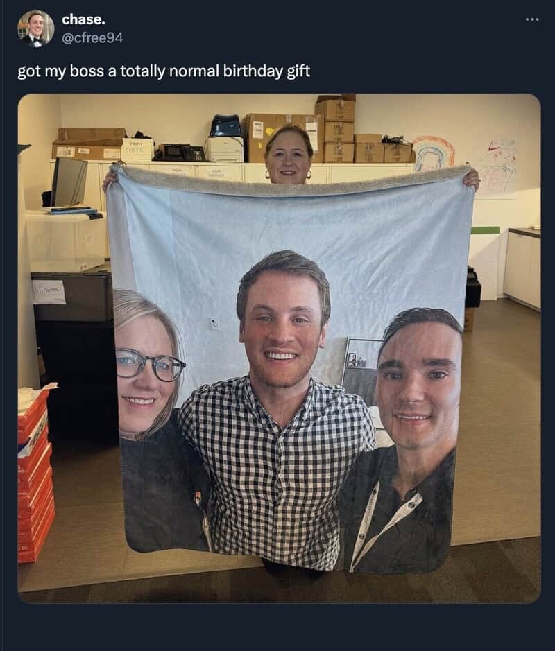 Person holding a blanket with a printed photo of three people, with a woman behind it.