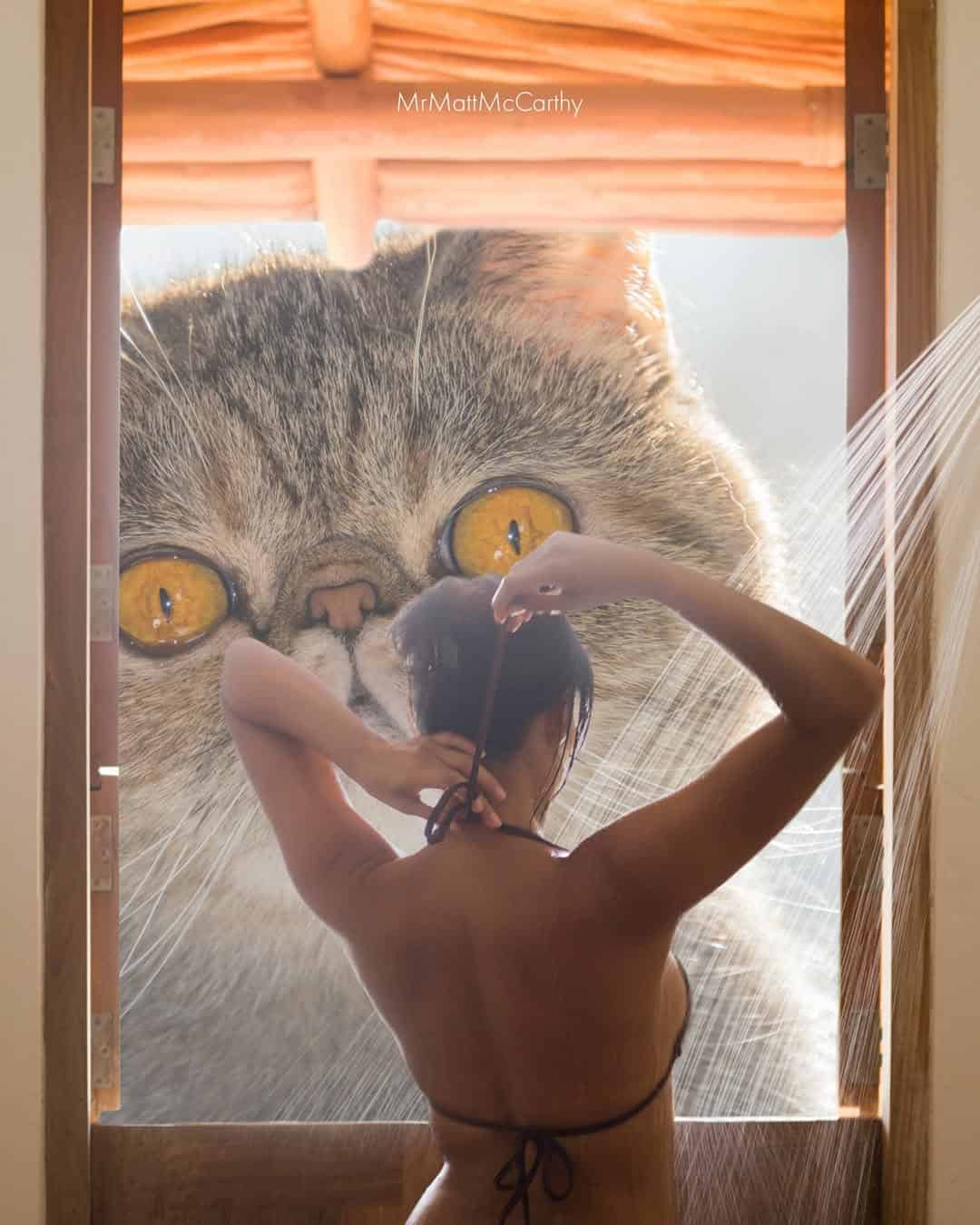 A woman with long hair looking out a window at a giant cat face outside.