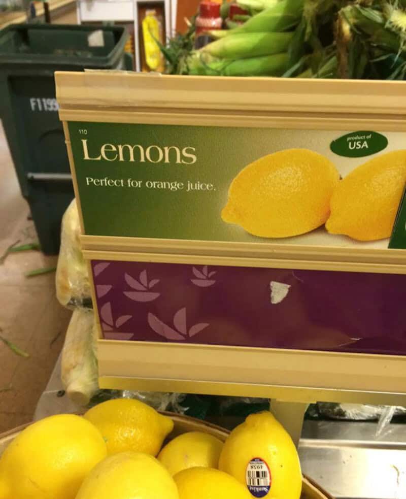 Lemons on a store shelf with a sign that says 'Lemons Perfect for orange juice'.