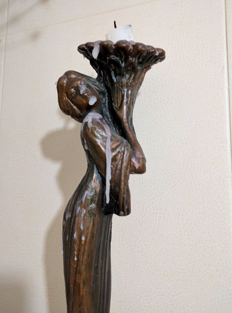 Hilarious sculpture of a girl holding a candle with wax dripping down.